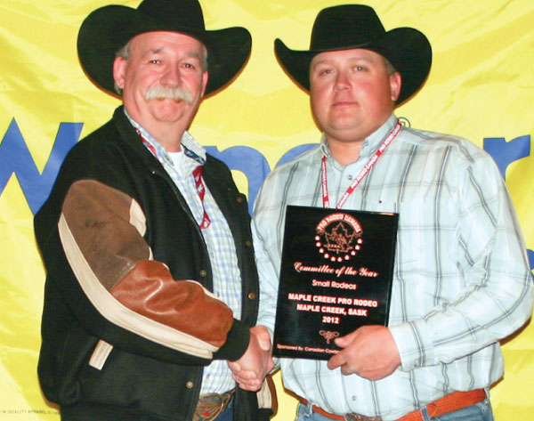 Slim Needham, on behalf of the Maple Creek rodeo committee, accepts the rodeo Committee of the Year Award (Small Rodeo) from sponsor representative Rob Tanner of Canadian Cowboy Country  