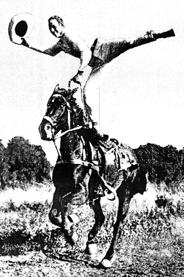 Ted Elder waving his hat while doing a one-leg stand on a galloping horse. Photo courtesy Raymond Museum.