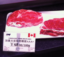 Top-grading Canadian ribeye steaks are prominently displayed at a Shanghai grocery store. The price converts to approximately $38 per pound.