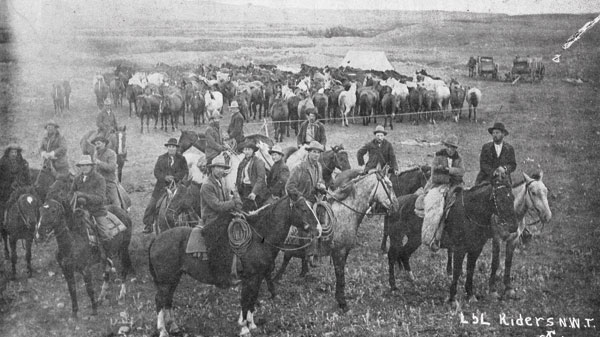 Group of cowboys riding for the LL brand on the annual round up in the NWT, now Alberta and Saskatchewan. Behind them are some of the horses in a rope corral. Although this photo was taken pre-1905 it is reflective of Ray’s early experiences.